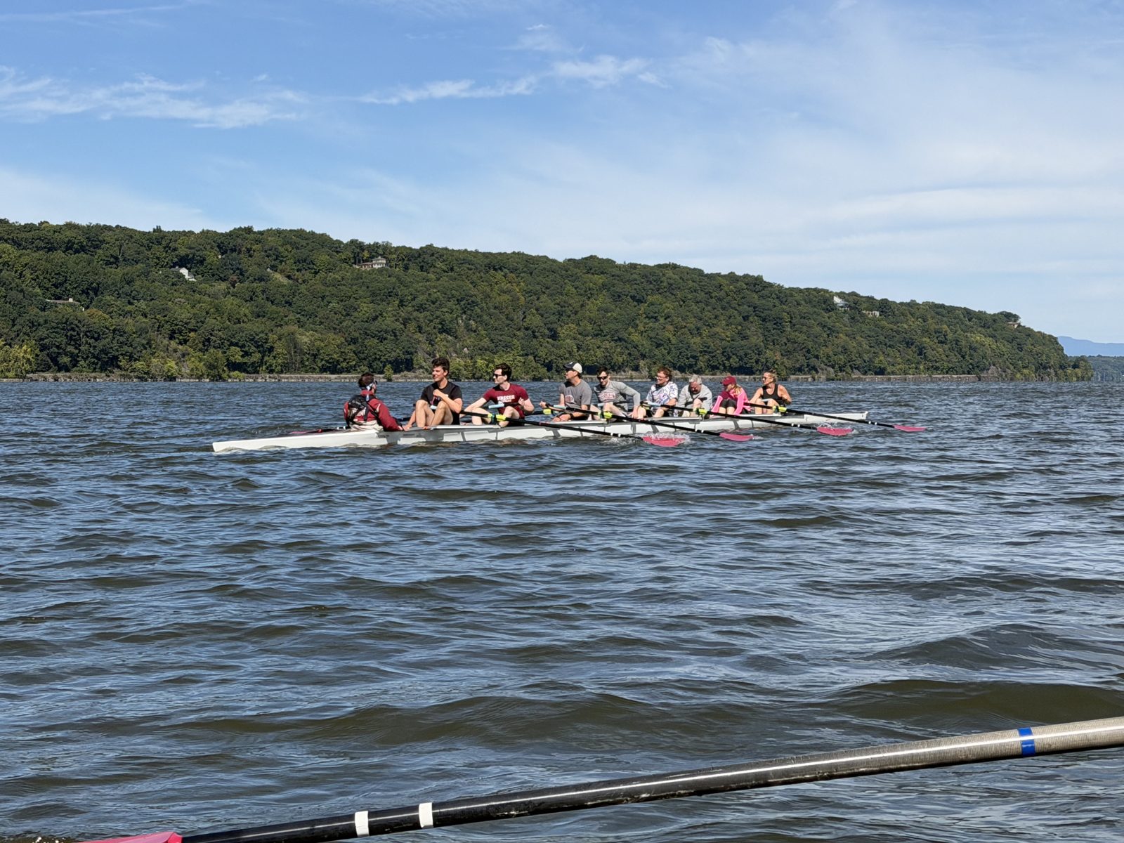 An eight rowing on the Hudson with the western ridge behind